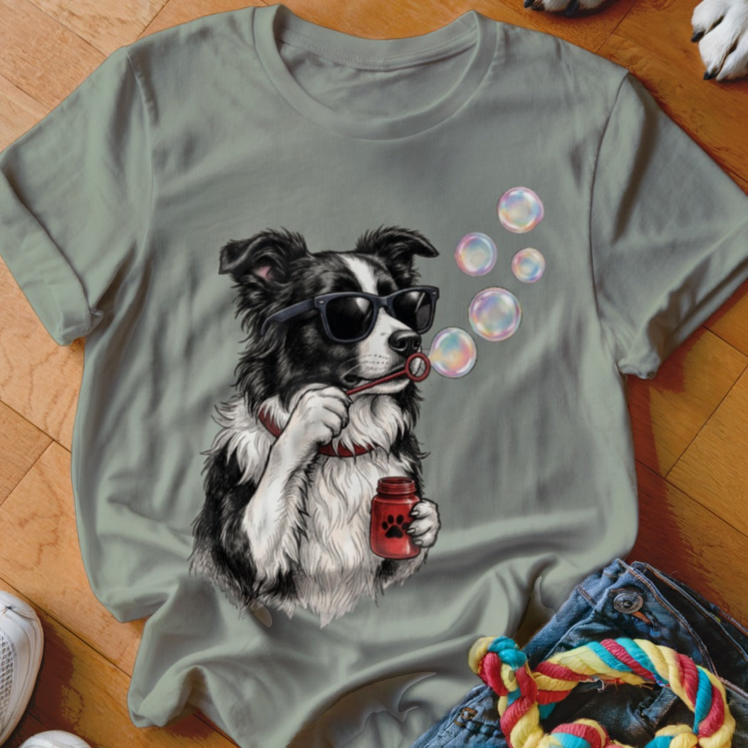 Sage green t-shirt featuring a graphic of a Border Collie wearing sunglasses and blowing soap bubbles.