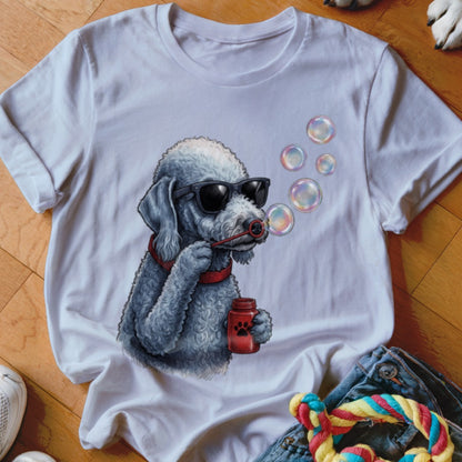 A white t-shirt featuring a graphic of a grey poodle wearing sunglasses and blowing bubbles.