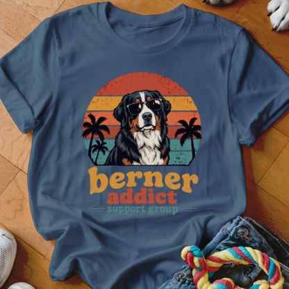 Blue t-shirt featuring a Bernese Mountain Dog wearing sunglasses in front of a sunset with palm trees and text reading berner addict support group.