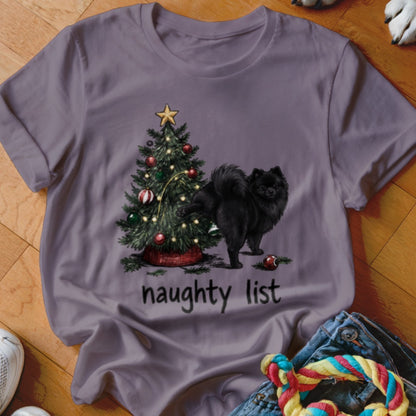Black Pomeranian near a Christmas tree with the text "naughty list".
