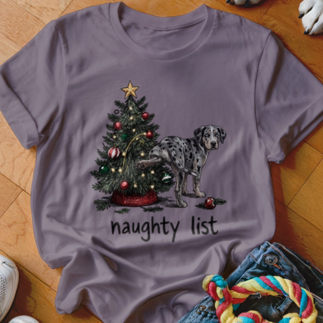 A purple t-shirt featuring a spotted dog peeing on a decorated Christmas tree with the text "naughty list".