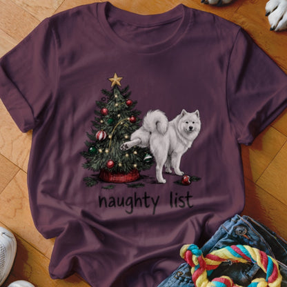 Dark purple t-shirt featuring a white dog lifting its leg against a Christmas tree, with the text naughty list.