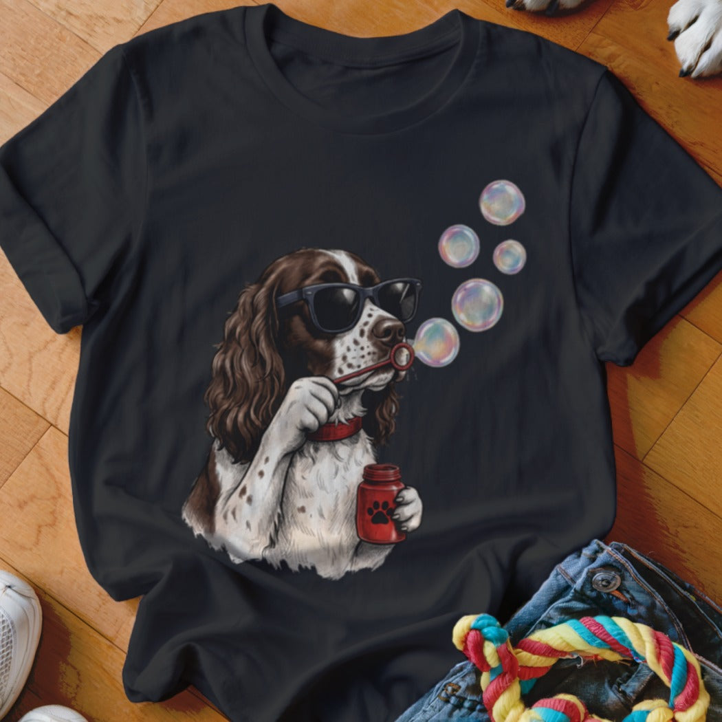 A black t-shirt printed with a graphic of a brown and white dog wearing sunglasses and blowing bubbles.
