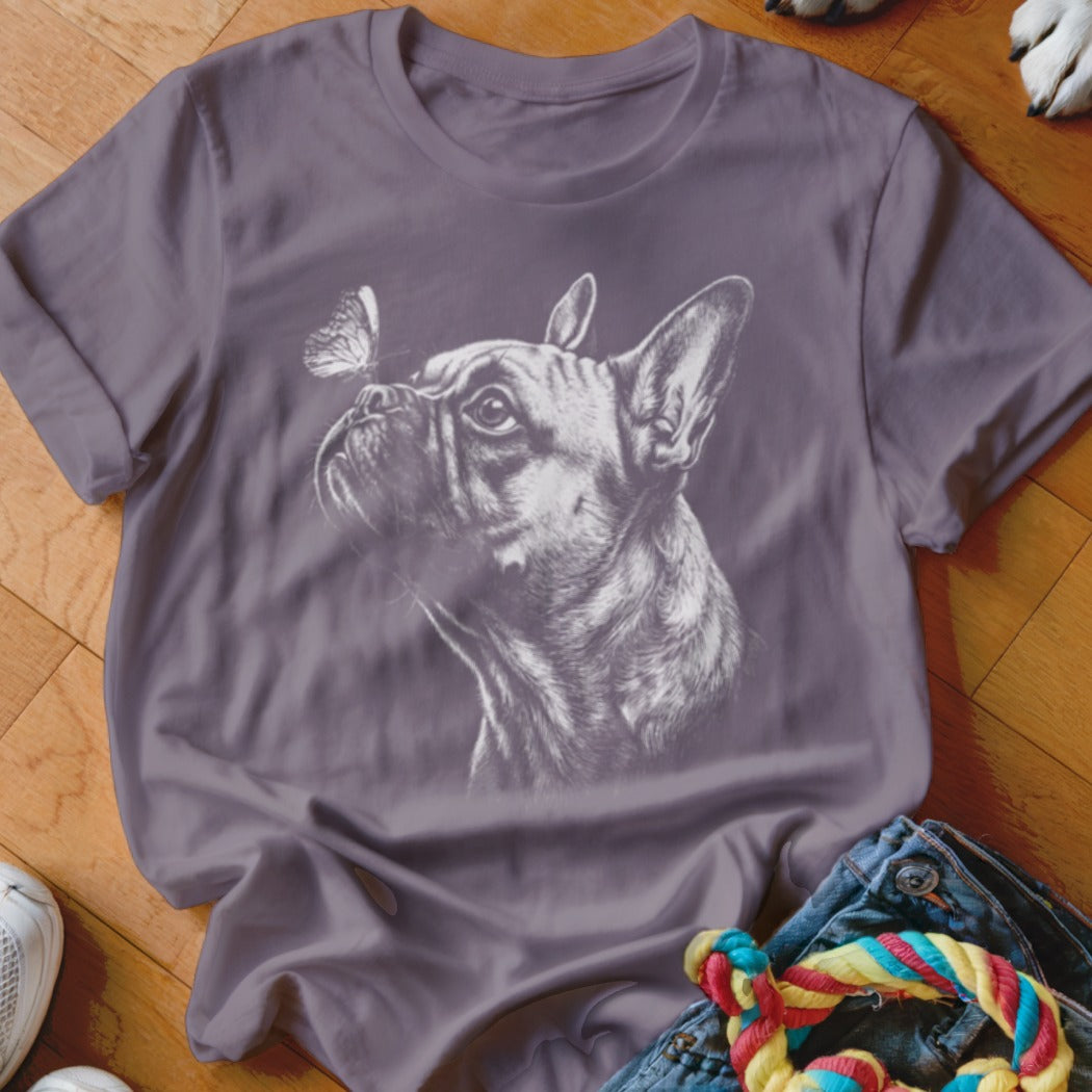 A purple t-shirt featuring a white sketch of a French bulldog looking at a butterfly.