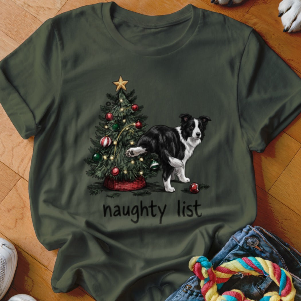 A dark green t-shirt featuring a graphic of a Border Collie lifting its leg on a Christmas tree, with the text "naughty list" below.