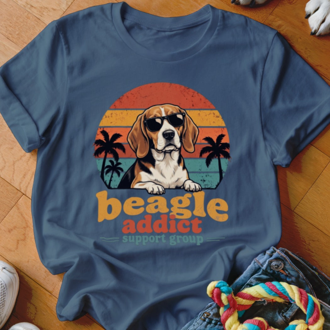 A blue t-shirt features a beagle wearing sunglasses in front of a retro sunset and palm trees graphic, with the text beagle addict support group underneath.