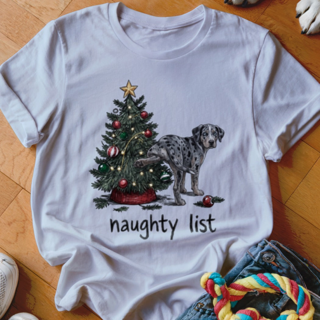 White t-shirt with a graphic of a spotted dog lifting its leg on a Christmas tree, with the text naughty list.