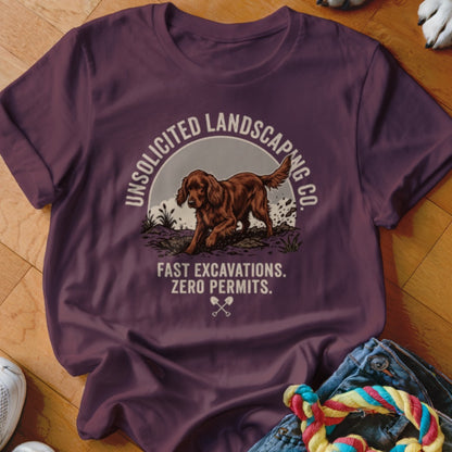 Brown dog on a t-shirt with text "UNSOLICITED LANDSCAPING CO. FAST EXCAVATIONS. ZERO PERMITS."
