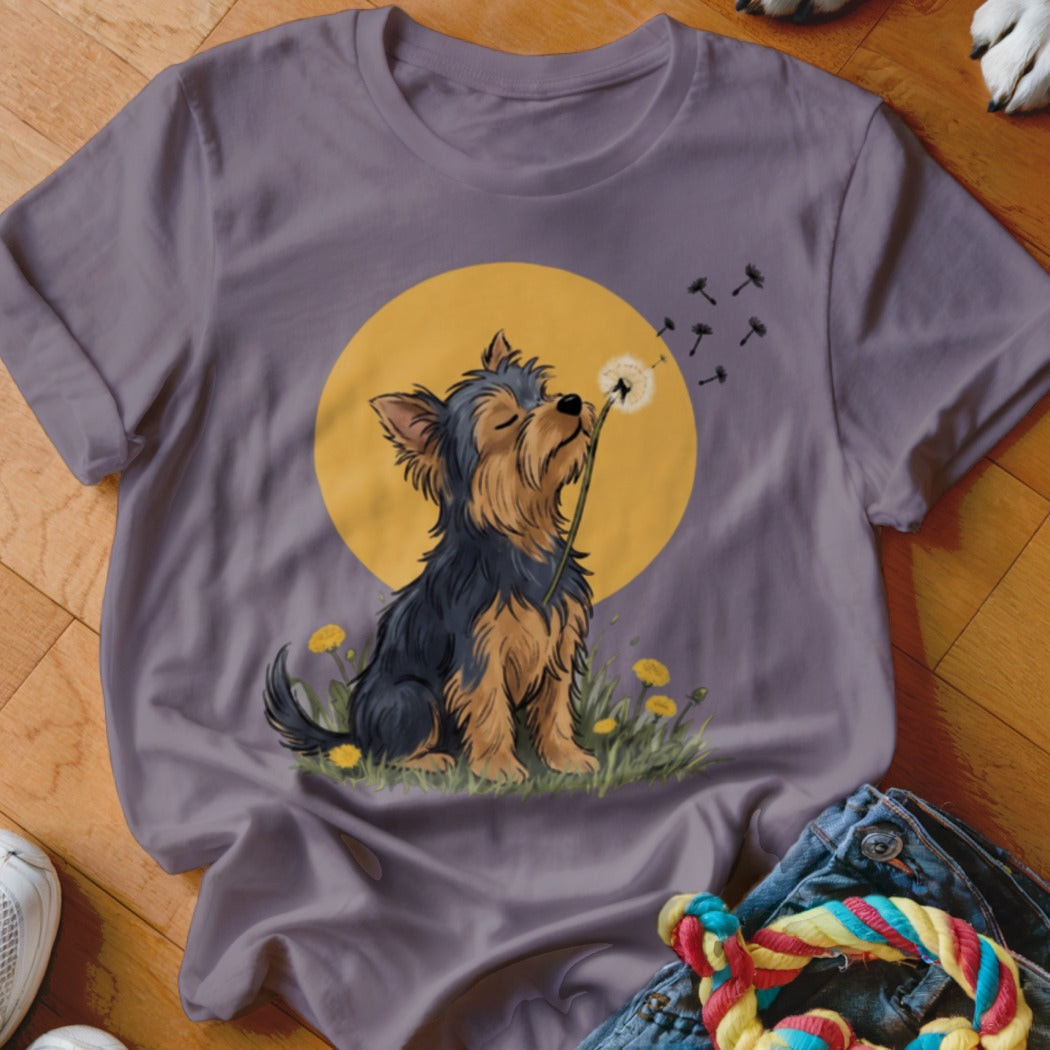 Purple t-shirt featuring an illustration of a Yorkshire Terrier blowing dandelion seeds against a yellow sun.