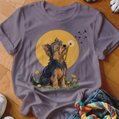 Purple t-shirt featuring an illustration of a Yorkshire Terrier blowing dandelion seeds against a yellow sun.