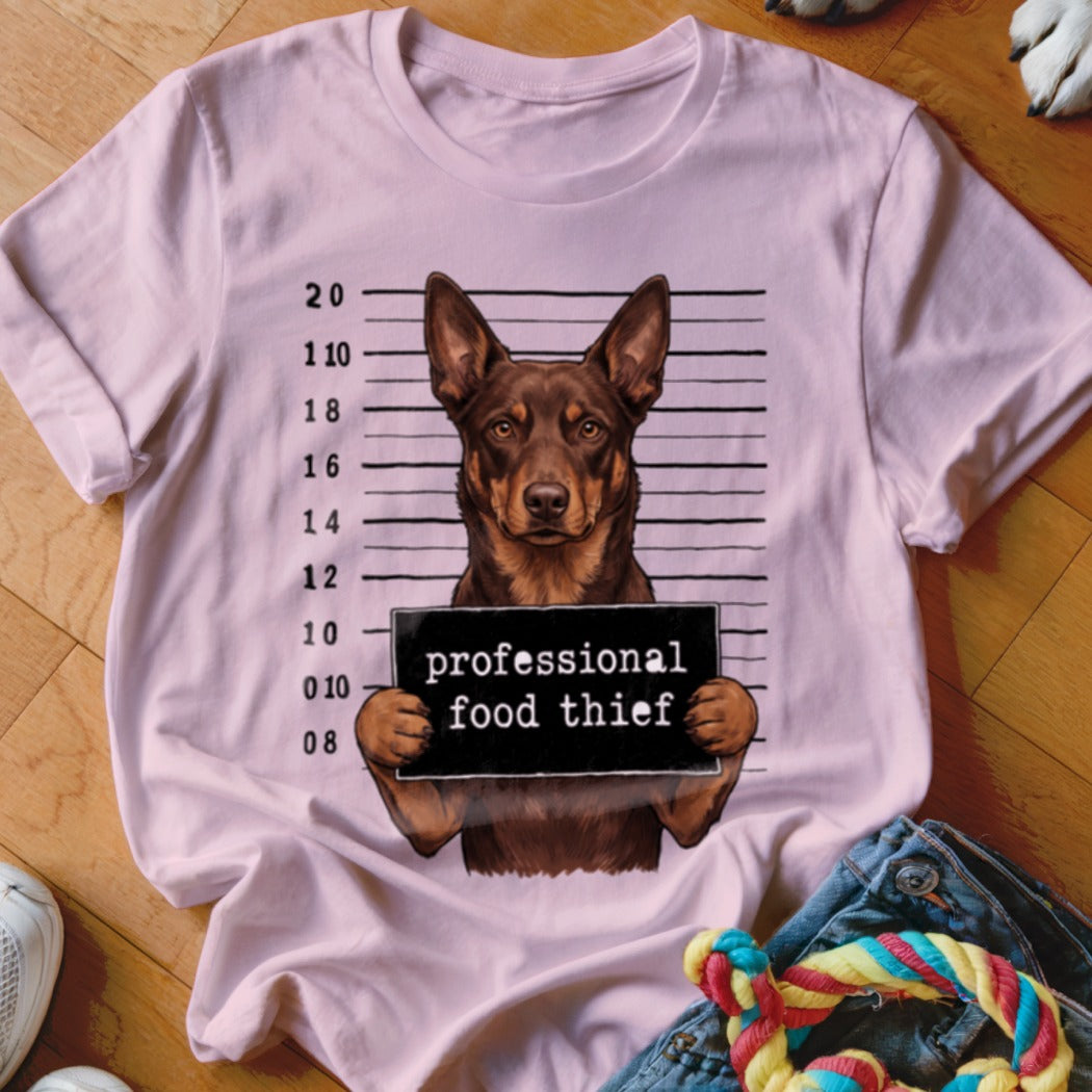 Dog mugshot with "professional food thief" sign on a pink t-shirt.