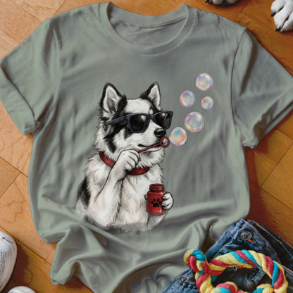 Olive green t-shirt featuring a graphic of a black and white dog wearing sunglasses and blowing soap bubbles.