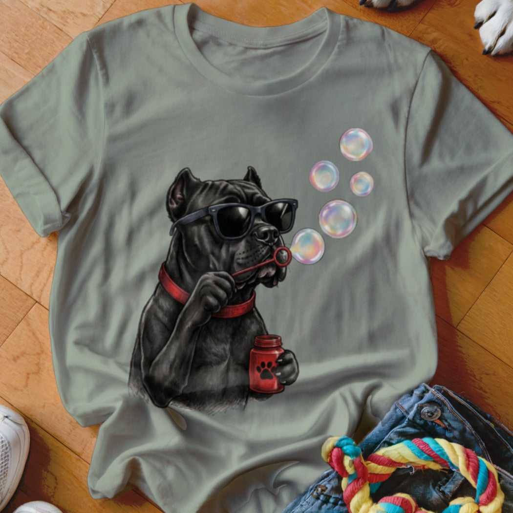 A sage green crewneck t-shirt featuring a graphic of a black dog wearing sunglasses and blowing bubbles.