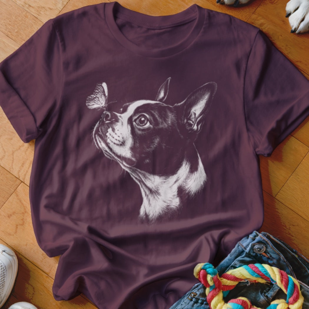 Maroon t-shirt featuring a white sketch graphic of a Boston Terrier looking at a butterfly on its nose.