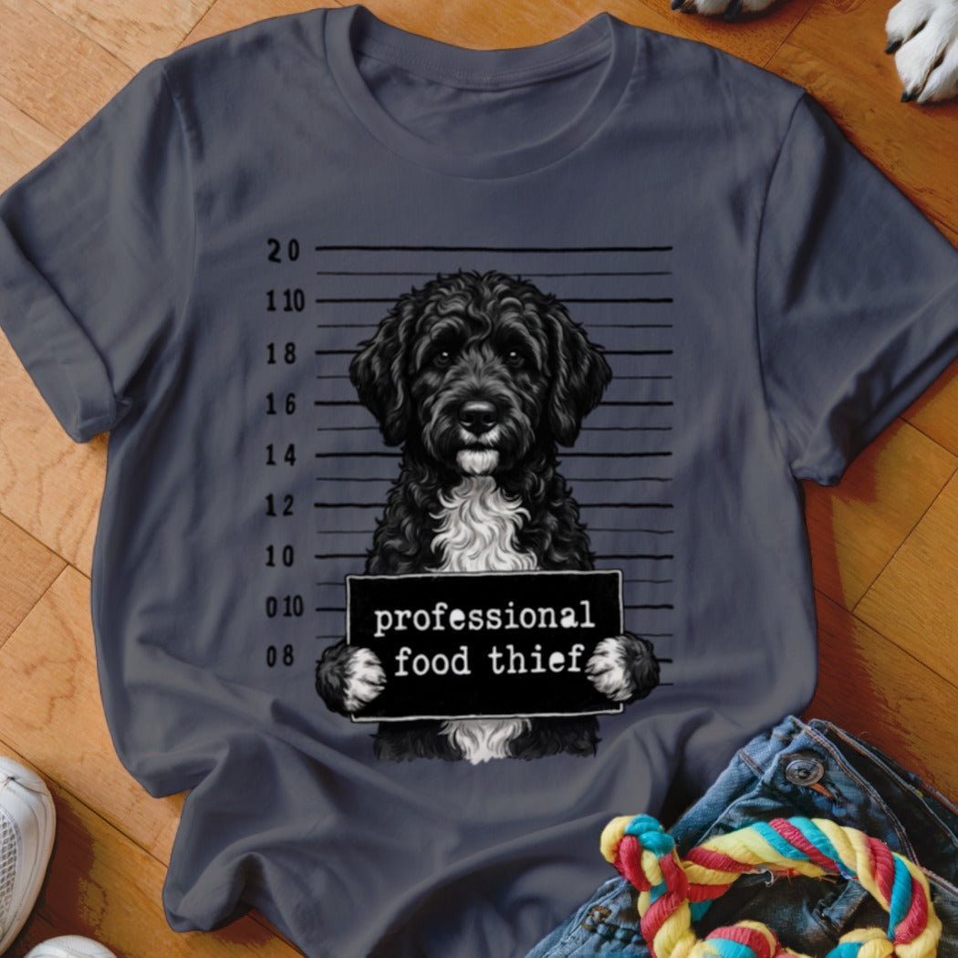 Black dog mugshot with "professional food thief" sign, on a grey t-shirt.