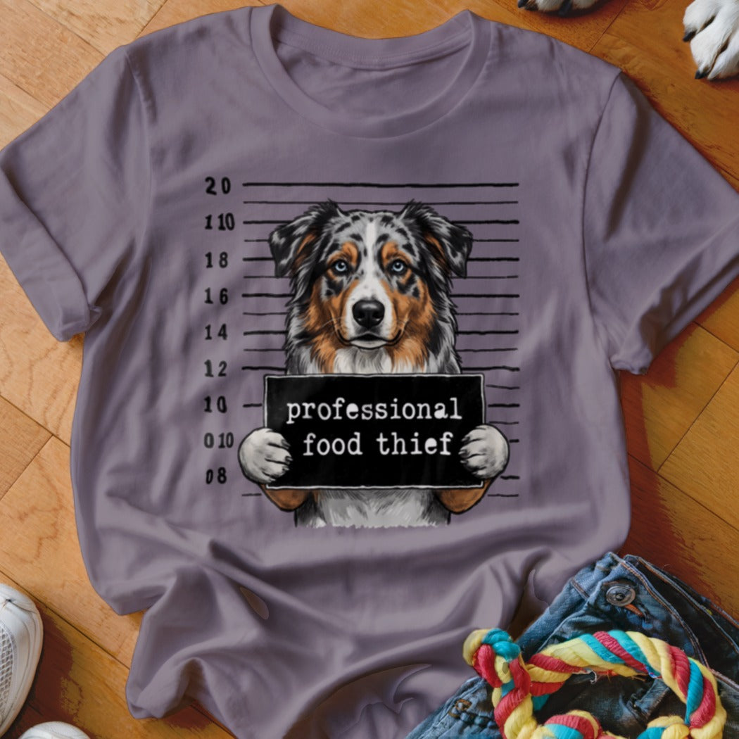 Australian Shepherd mugshot with "professional food thief" sign.