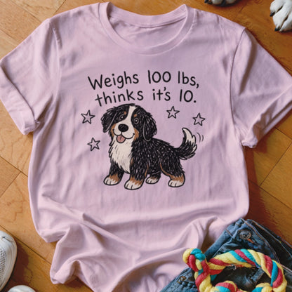 Pink t-shirt with cartoon Bernese Mountain Dog and text "Weighs 100 lbs, thinks it's 10."