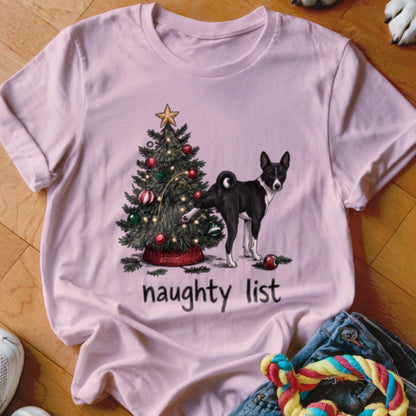 Light pink t-shirt featuring a graphic of a black and white dog lifting its leg at a decorated Christmas tree with the text naughty list.