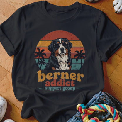 A black t-shirt features a Bernese Mountain Dog wearing sunglasses against a retro sunset and palm tree graphic.