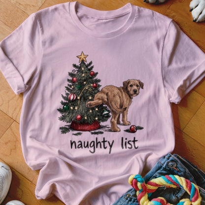 A pink t-shirt features a graphic of a dog lifting its leg on a Christmas tree, with the words naughty list underneath.