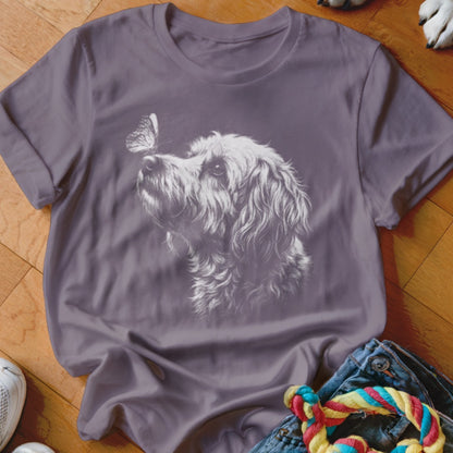 A purple crewneck t-shirt featuring a white line drawing of a fluffy dog and butterfly.