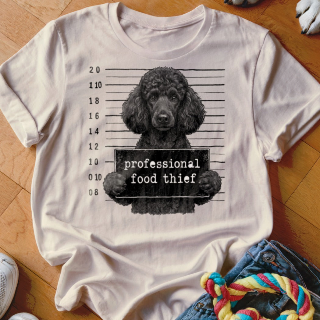 T-shirt graphic of a black poodle holding a sign that says "professional food thief".