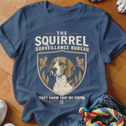 A dark blue t-shirt featuring a beagle graphic, shield design, and text reading The Squirrel Surveillance Bureau.