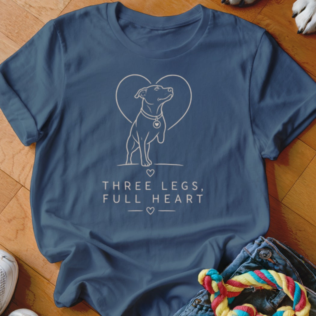 Blue t-shirt with line art of a three-legged dog inside a heart, text "THREE LEGS, FULL HEART".