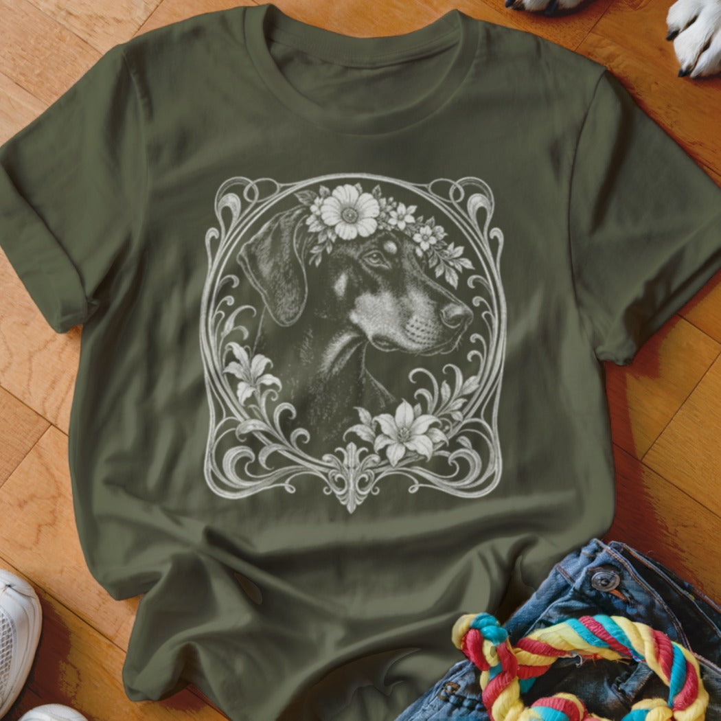 Green t-shirt featuring a black and tan dog wearing a flower crown within an ornate frame.