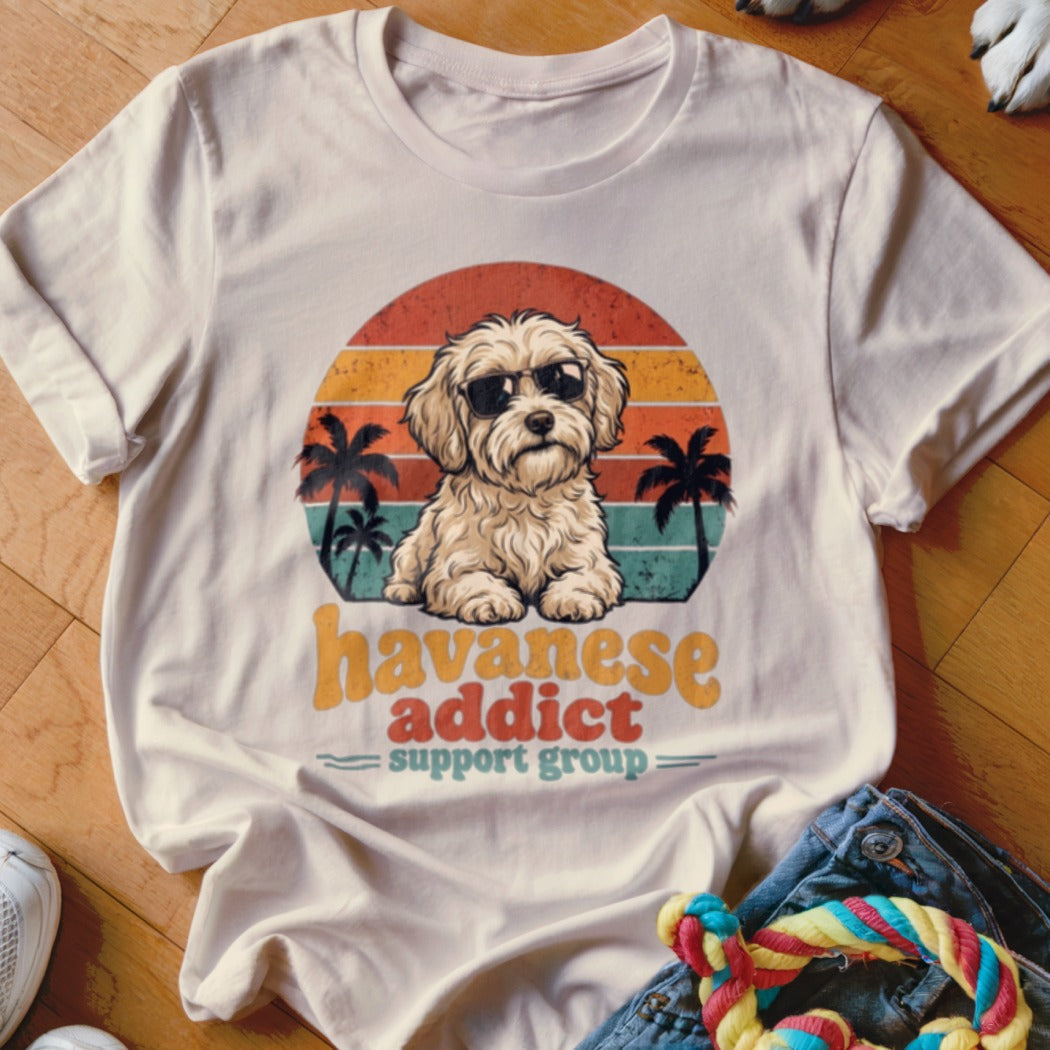 Light-colored t-shirt featuring a retro sunset graphic, a Havanese dog wearing sunglasses, and text reading "Havanese Addict Support Group".