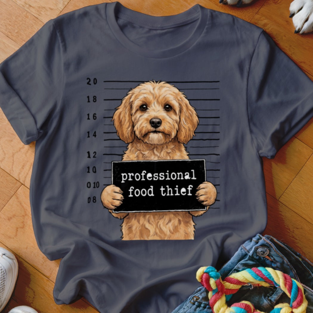 T-shirt graphic of a fluffy dog holding a sign that reads "professional food thief".