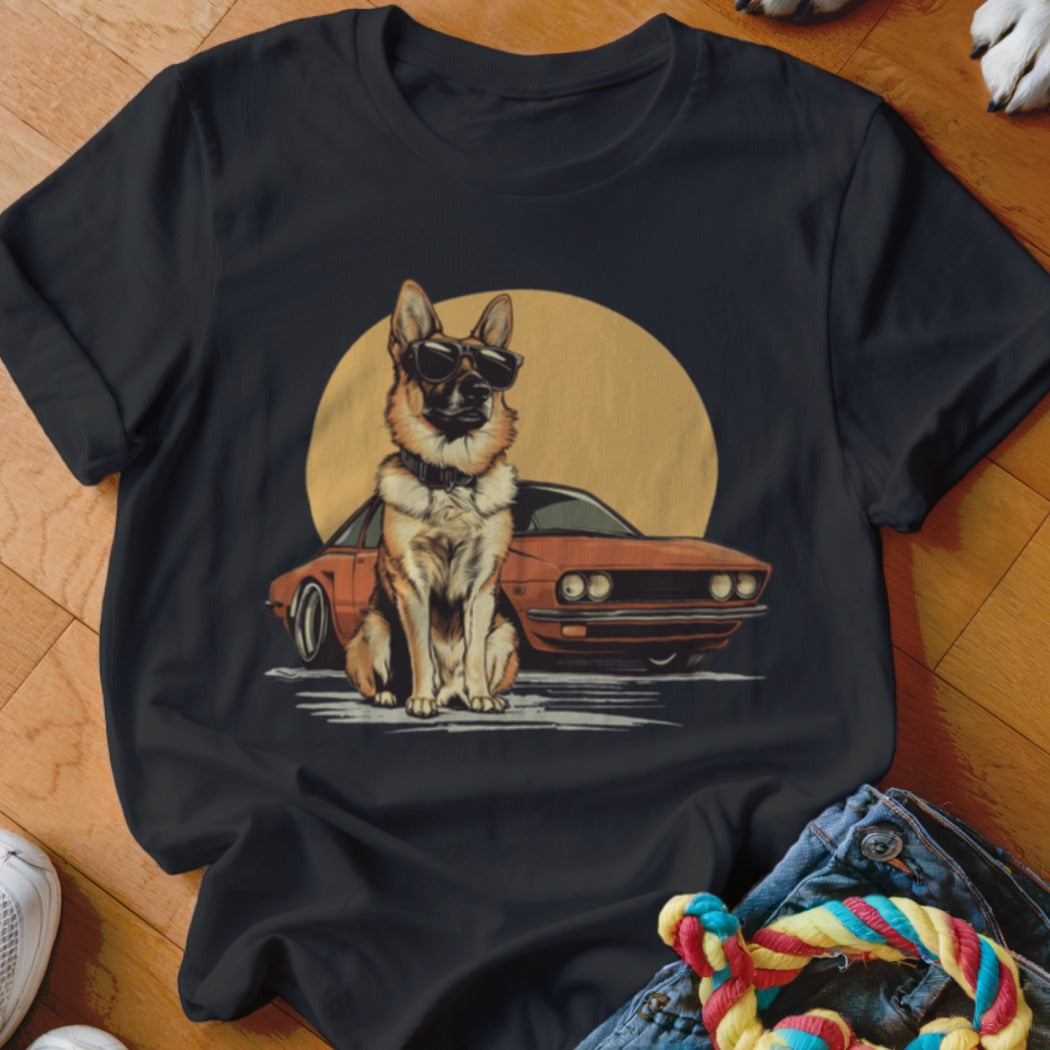 German Shepherd with sunglasses sits in front of an orange car and yellow sun.